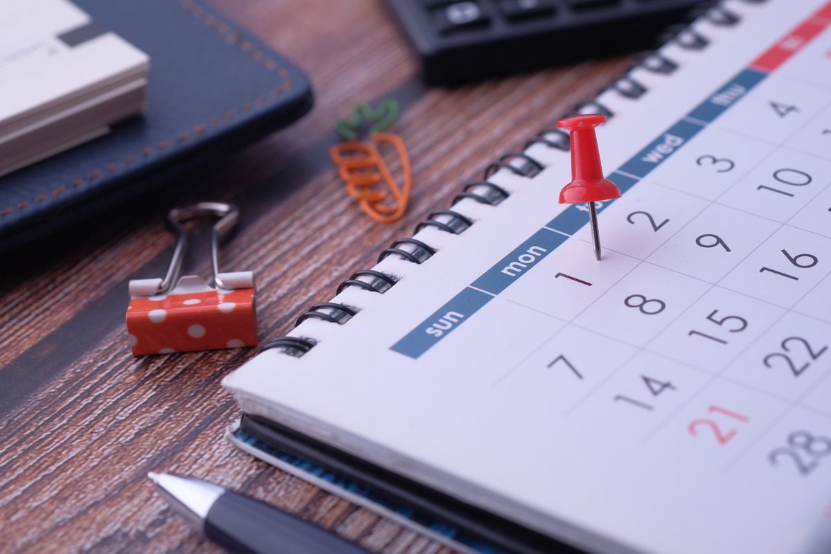 Calendario con una fecha marcada con un pin, sobre un escritorio