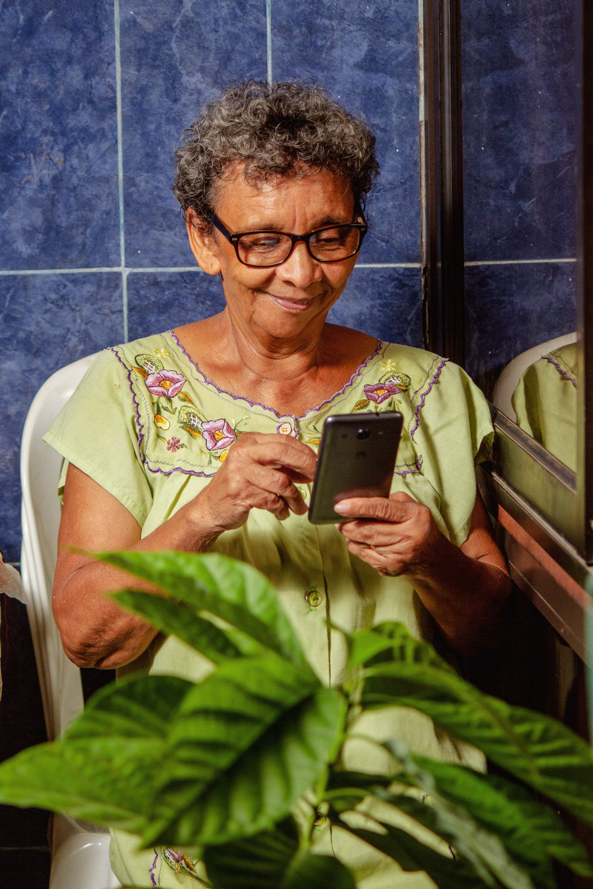 Mujer mayor sonriendo mientras usa su celular