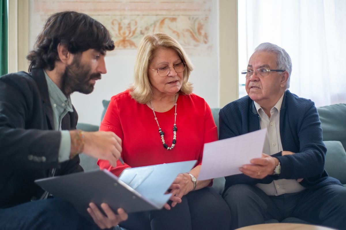Pareja de adultos mayores revisando documentos junto a su asesor